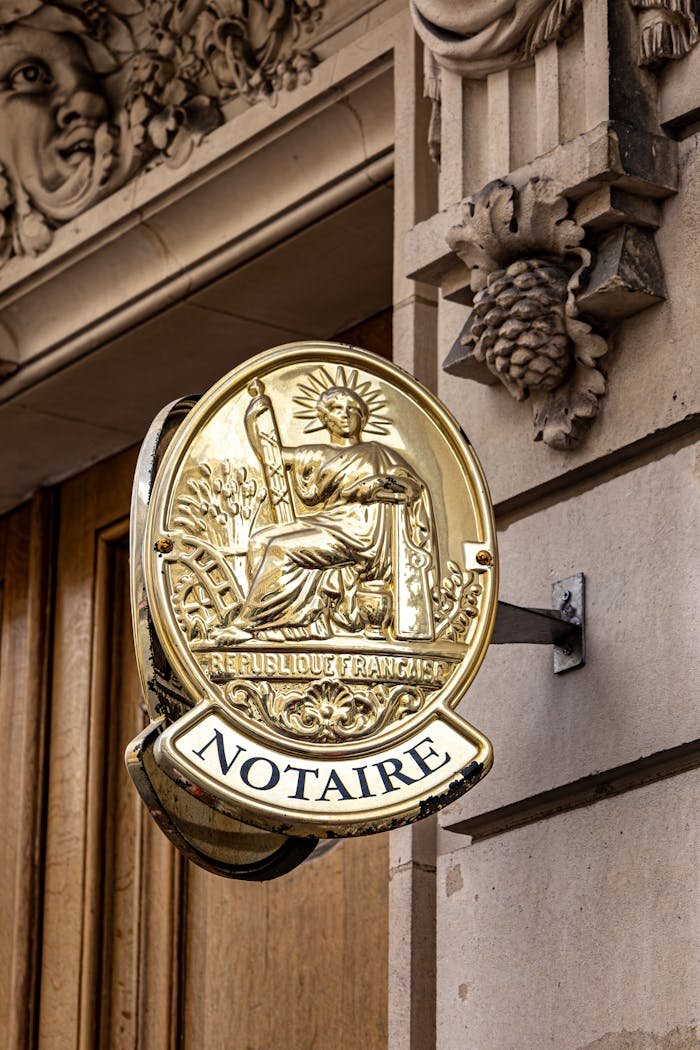 Classic notary sign on a historic Parisian building facade in daylight.