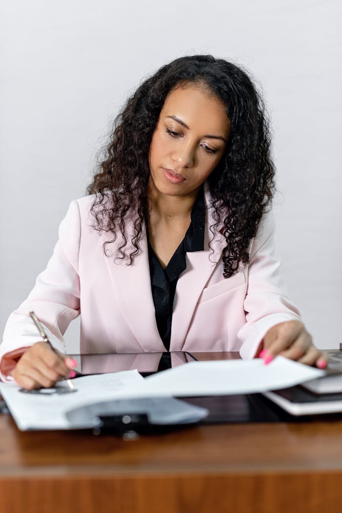 Focused businesswoman signing important documents at her office desk.